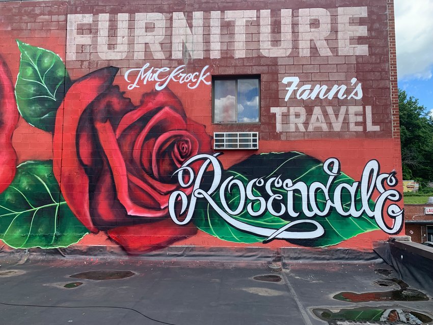 A large mural of painted roses by the artist Muckrock above Rosendale's MyTown Marketplace pictured at eye level from the room top.