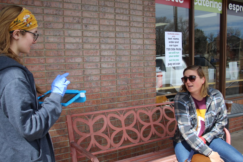 Attie Schuler, left, takes an order from Lakewood resident Hannah Bouska outside Village Roaster Coffee and Tea in Lakewood. Eric Bakken, owner of the tea and coffee shop, said he had to lay off 18 of his 26 employees because of the COVID-19 pandemic.