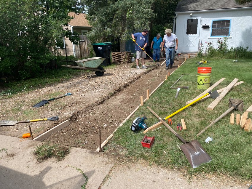 Joshua Regan, left, and Charles Wooldridge, right, worked on replacing the old front walkway at the home of Virginia Keller, center, during Englewood's Day of Service on June 18, 2022.