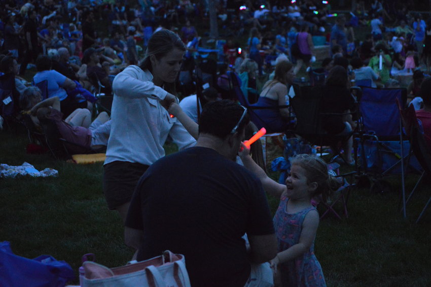 Jade Faucheux, 3, waves her glow stick in front of her dad, Alex Faucheux, as her sister dances with her mom at Centennial Center Park on Aug. 13, 2022.