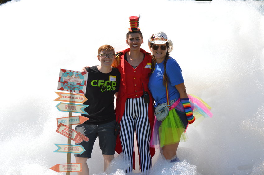 From left to right: Hayley Wolfe, Logan Ellett and Jaalah Neerhof of Collaborative Foster Care Program smile as they stand in front of the pile of foam at the Aug. 13, 2022, event.