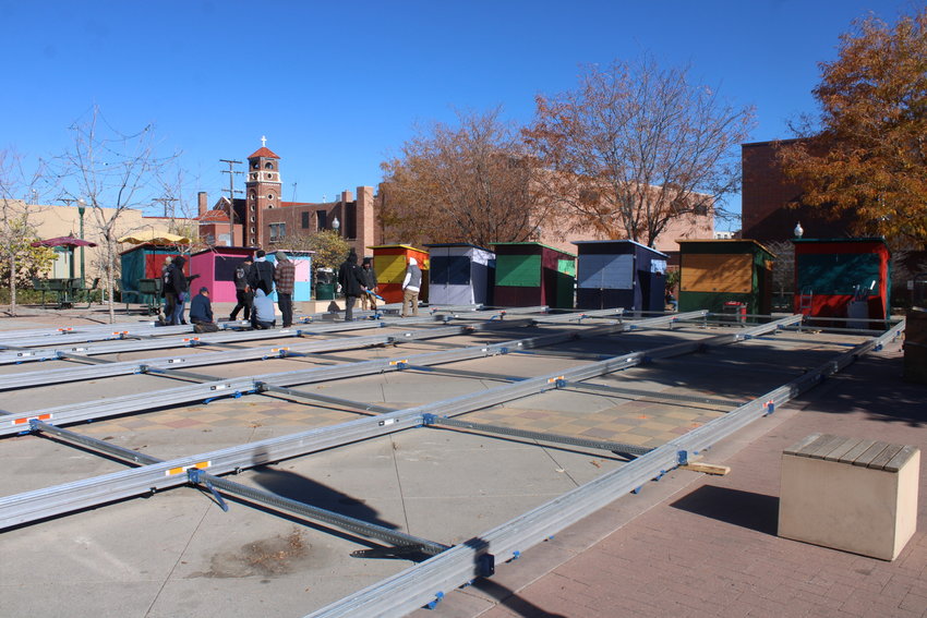 As crews work to set up the ice rink in Olde Town Square, the Holiday Market stalls are set up.