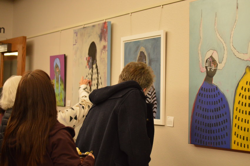 People viewing and discussing Danielle SeeWalker's art pieces at Koelbel Library on Nov. 10