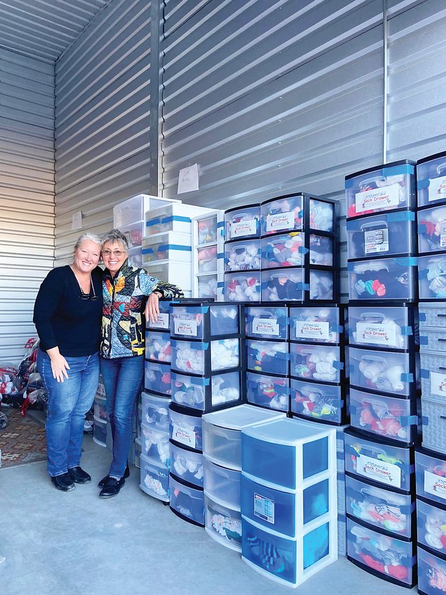 Tammie Limoges, the chief development and operations officer of the nonprofit, smiles alongside Sue Lee, showing off the sock drawers in the nonprofit's storage.