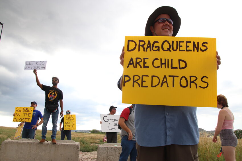 Protesters hold up signs near the entrance at the Douglas County Fairgrounds Aug. 26 during Douglas County PrideFest.