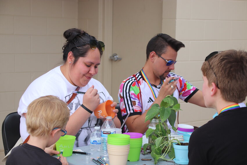 Douglas County residents Destiny Flores and Ryan Pinkas-Hernandez paint plant pots at PrideFest on Aug. 26.