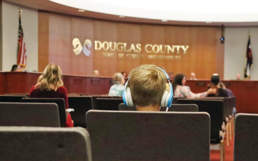 A boy listens to his headphones as Douglas County Board of Health members debate allowing students and teachers to opt out of masking mandates in schools at an Oct. 8, 2021, meeting.