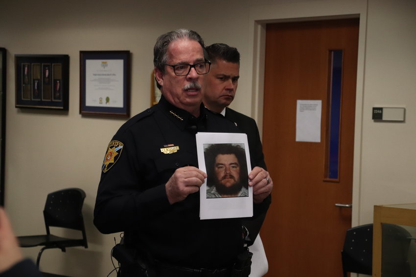 Douglas County Sheriff Tony Spurlock holds up a photo of Casey Devol at a media briefing on Wednesday. Devol is the suspect in a double homicide that occurred Tuesday.