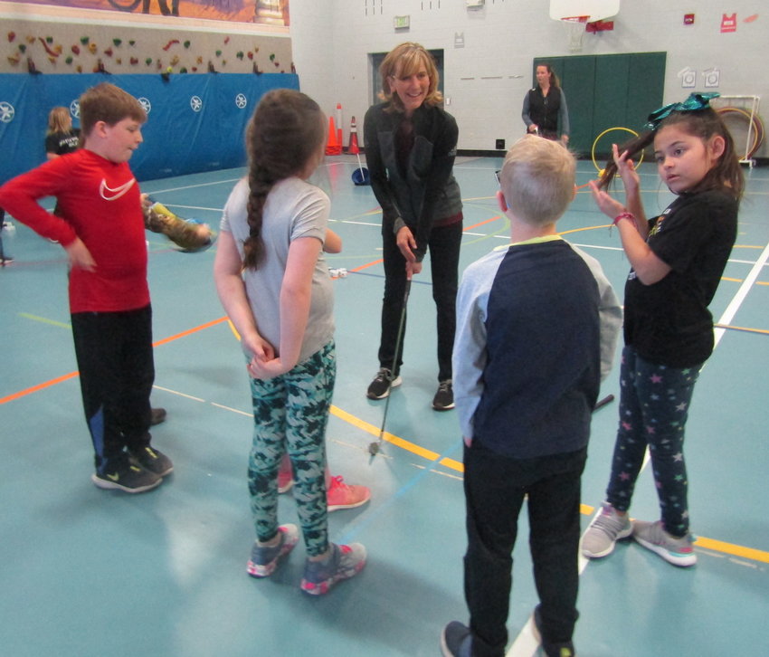First Tee coach Jill Boerner talks with a group of students about the proper golf swing techniques.