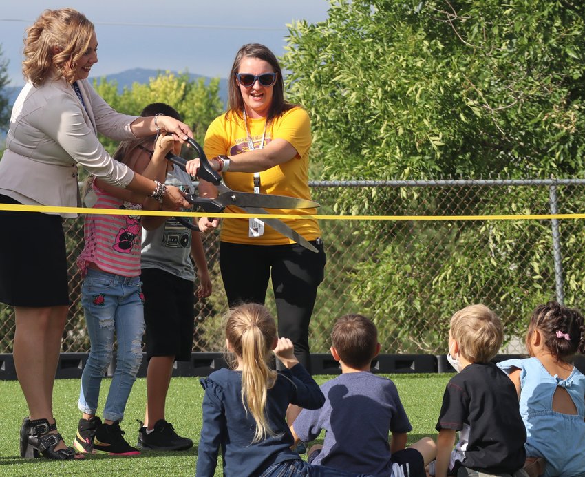 Field Elementary Assistant Principal Amber Struthers, left, and Parent Teacher Organization President Amy McCandless help kindergarten students cut the ribbon on the school's new turf field.