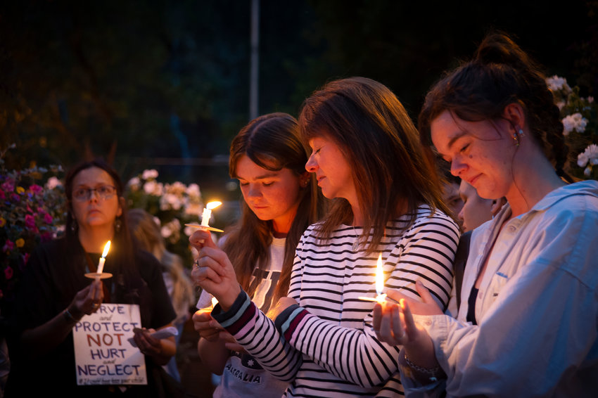 Sally Glass,center, mother of 22-year-old Christian Glass who was shot by police after calling 911 for help, is flanked by his sisters Katie, left, and Anna, right as they attend a candlelight vigil in Idaho Springs, Colorado Sept. 20, 2022.