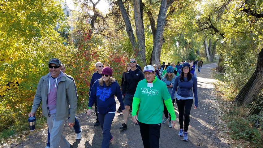 Dr. Ira Dauber, wearing a green Walk with a Doc shirt, enjoys a nature walk with patients and other community members.
