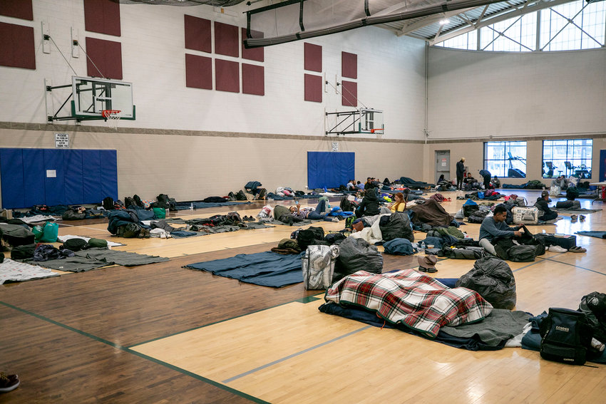 People who&rsquo;ve arrived from the U.S. southern border hang out on bedrolls on the floor of a Denver rec center, the city&rsquo;s second emergency shelter. People were originally given cots, but a city spokesperson said they switched to mats to squeeze more people in when they neared capacity in late December.