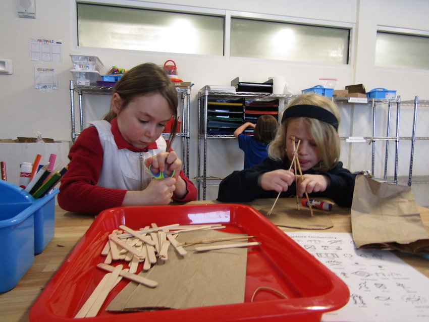Kindergartners Delaney Hough and Mila Franklin concentrate on making tepees in the Rocky Mountain Academy of Evergreen STEAM lab.