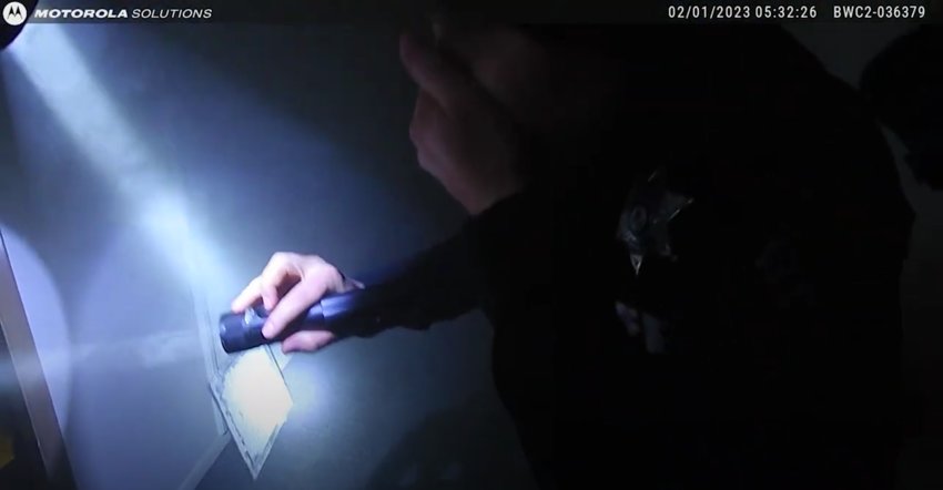 A screenshot of an Arapahoe County deputy's bodycam footage shows an officer holding a flashlight and a hand over his mouth in thick smoke inside Club Valencia.