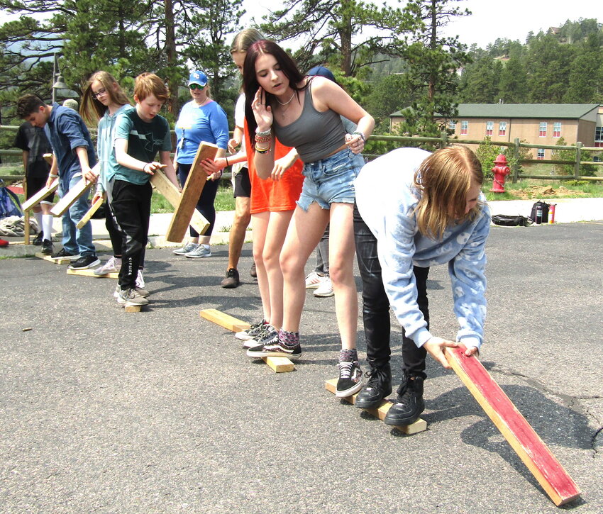 Seventh grader Sidney McCarter, right, and eighth grader McKenna Clark lead a group as it tries to cross a pretend river by stepping on wooden boards. Anyone who falls off a board must move to the end of the line. The game helped create teamwork among students at the annual Duster Day at Clear Creek Middle School.