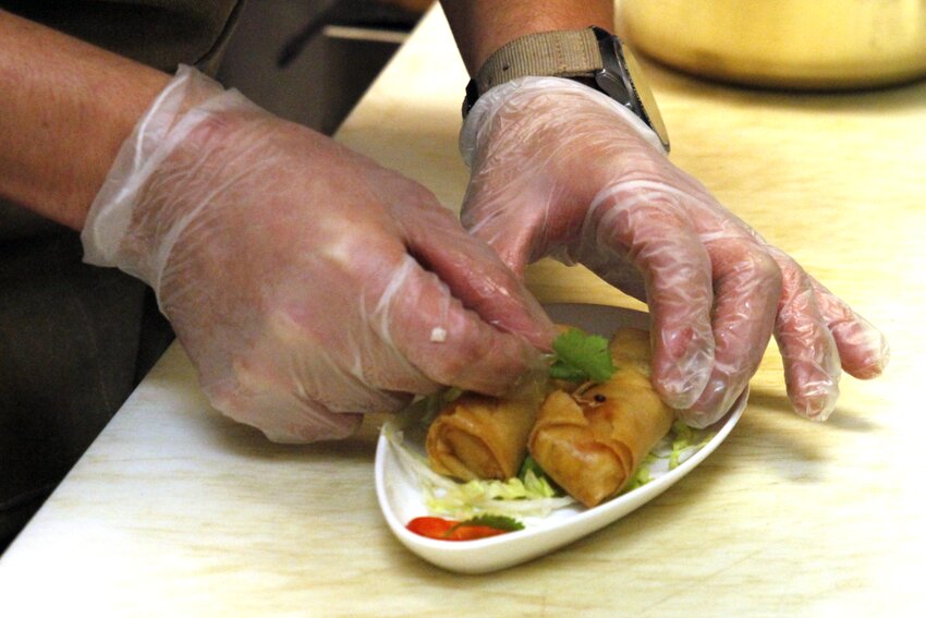 Kitchen assistant Josue Benavides garnishes a pair of spring rolls at Lone Tree&rsquo;s Honey Pig Cafe on Sept. 6.