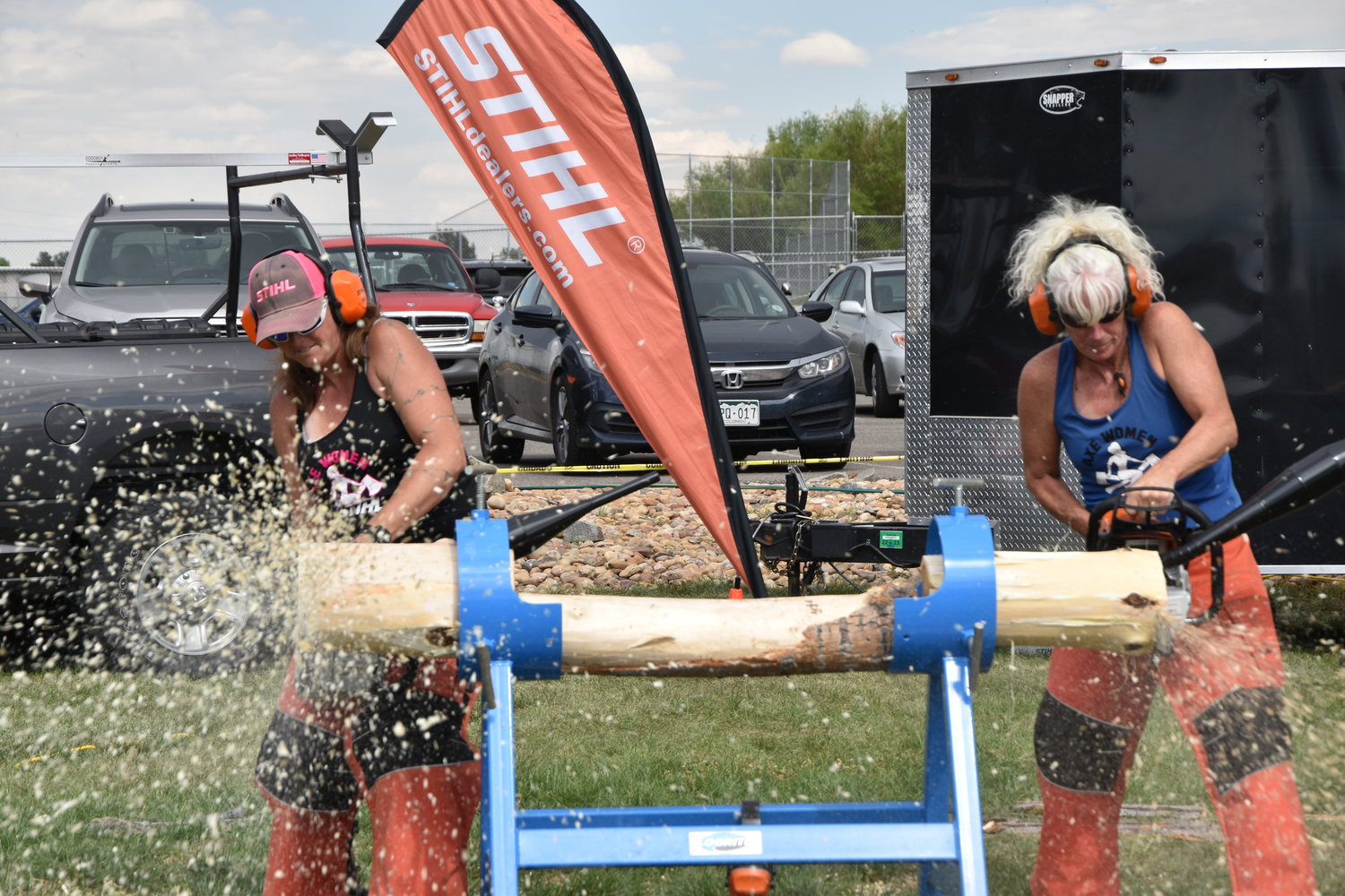 Allisa Weatherbee and Andrea Robarge competing who can carve off the end off the tree stump the quickest.