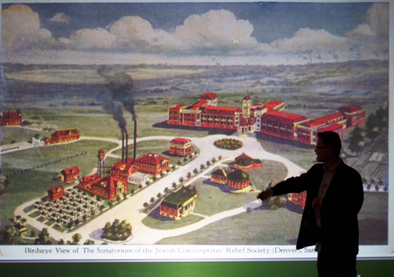 RMCAD Professor Thomas Keefe points to a slide featuring an artist's depiction of the early JCRS campus.