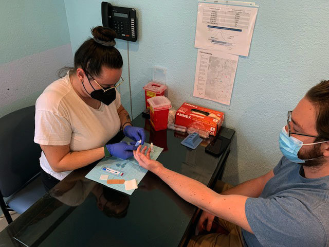 Mariah Frank, prevention director at the Boulder County AIDS Project, administers a finger prick rapid test to measure for presence of HIV and Hepatitis C.