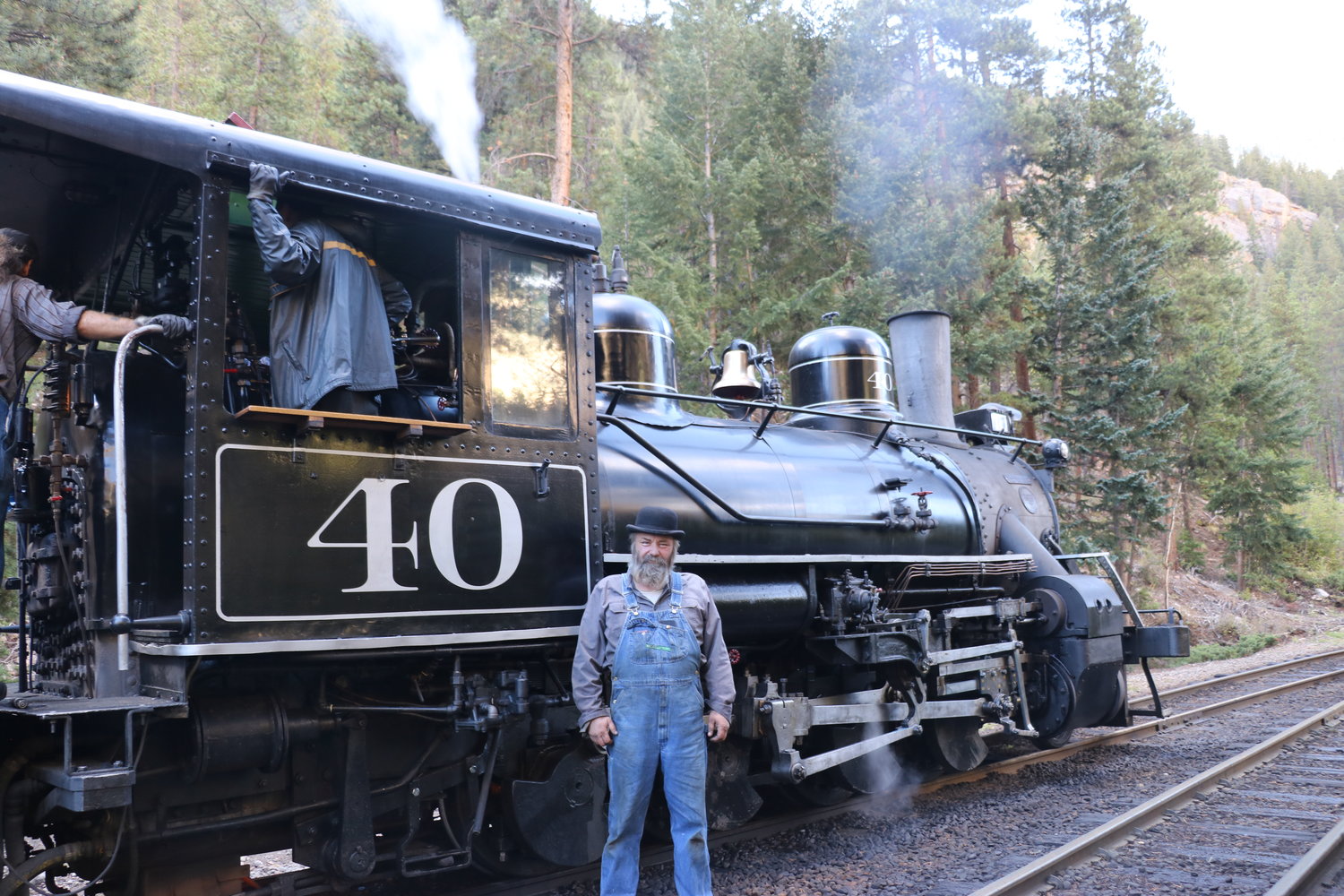 Mayor Sam McCloskey stands in front of one of the steam engines he works on.