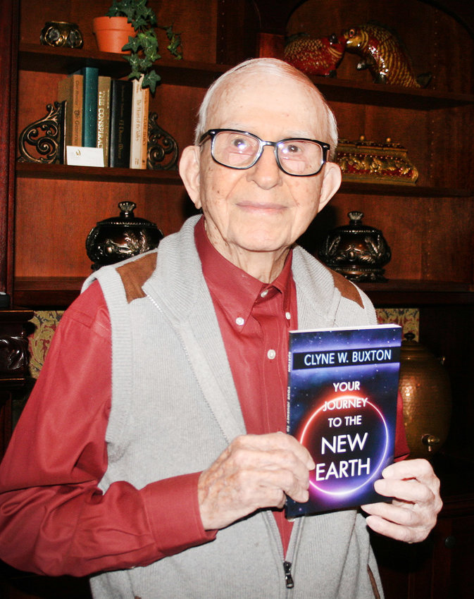 CLYNE BUXTON holds a copy of his book &quot;Your Journey to the New Earth.&quot;