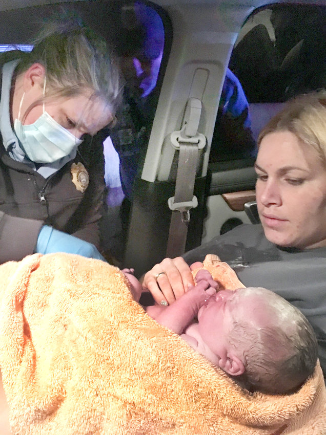 LESLIE NUNNELLY holds her newborn as a first responder unbuckles her seat belt Jan. 17. Her baby, Charlotte Jane, was born a day early as Leslie and her husband, Drew, were driving to a hospital in Chattanooga.