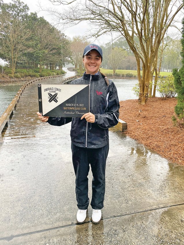 LADY FLAMES' GOLFER Alex Naumovski shows off her award through the rain after winning the individual title at the Emerald Coast Challenge in Sandestin, Fla., Tuesday.