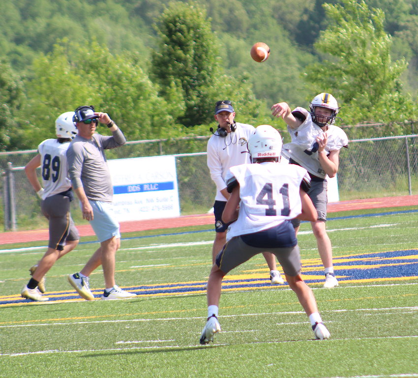 MUSTANGS QUARTERBACK Evan Schwarzl (1) throws to Travis Coley (41) as Mustangs coach Drew Akins, left, looks on during an offensive drill Wednesday, at Walker Valley.