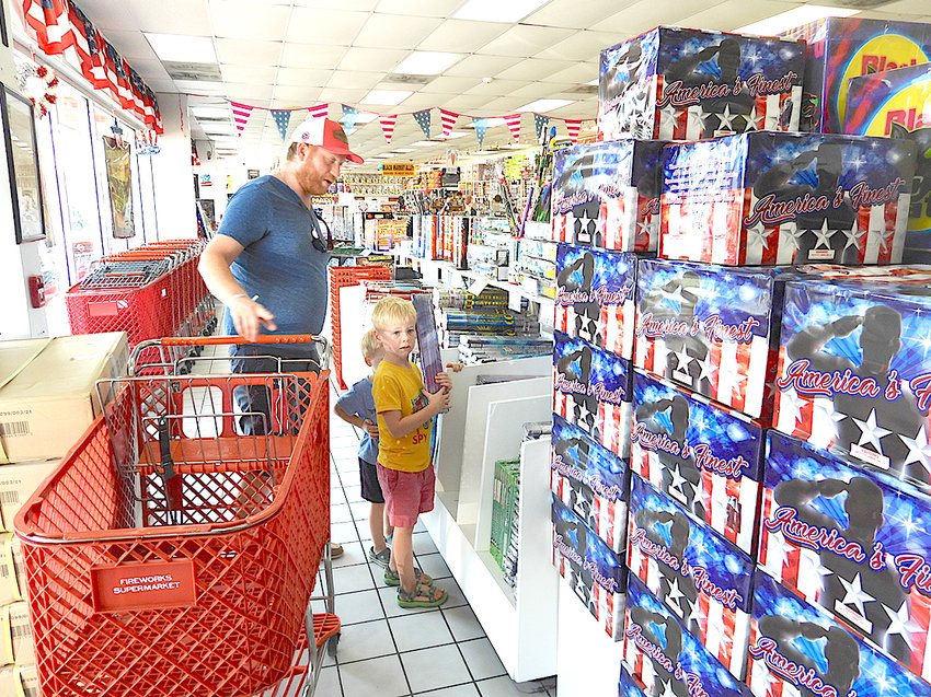 MICHAEL FULGHUM and his sons, Charlie and Benton, try to decide on which fireworks to purchase from the Fireworks Supermarket for their own home display.