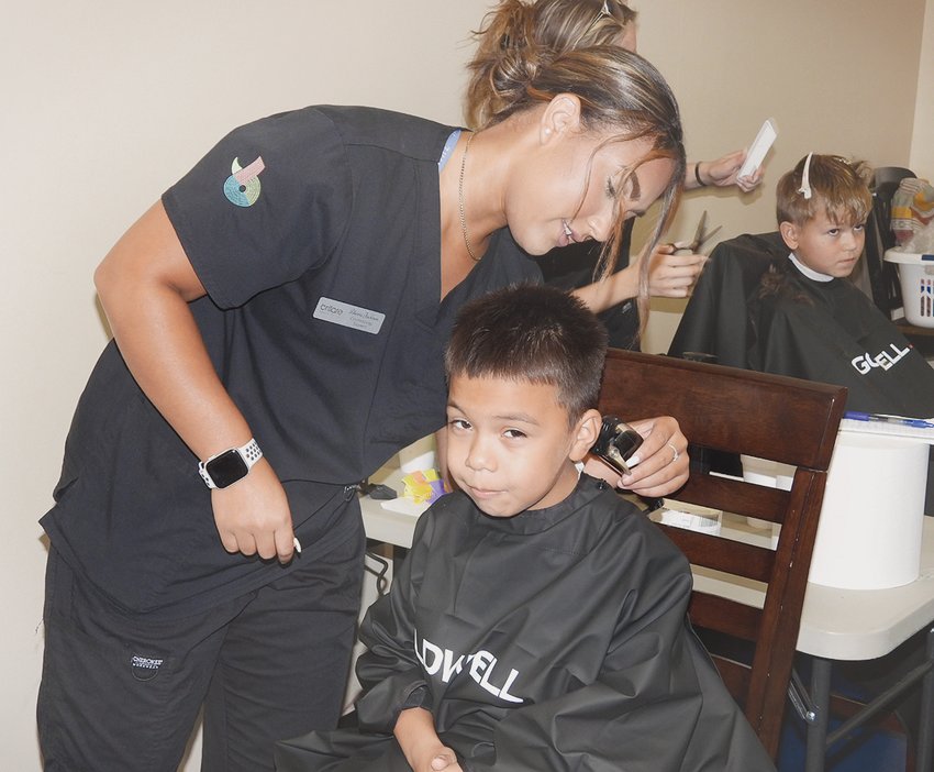 BYRON DIAZ, 7, receives a free haircut from one of the many stylists &mdash; Alexia Jackson of Brillare &mdash; at the Peerless Road Church back-to-school event.