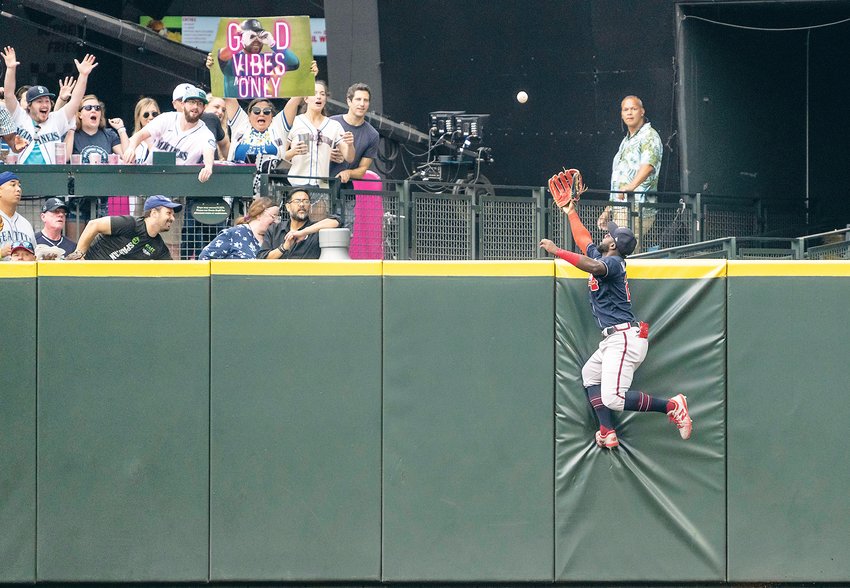 Atlanta Braves centerfielder Michael Harris II climbs the outfield wall in an attempt to get to a home run ball hit by Seattle Mariners' Eugenio Suarez during the fifth inning Sunday in Seattle.