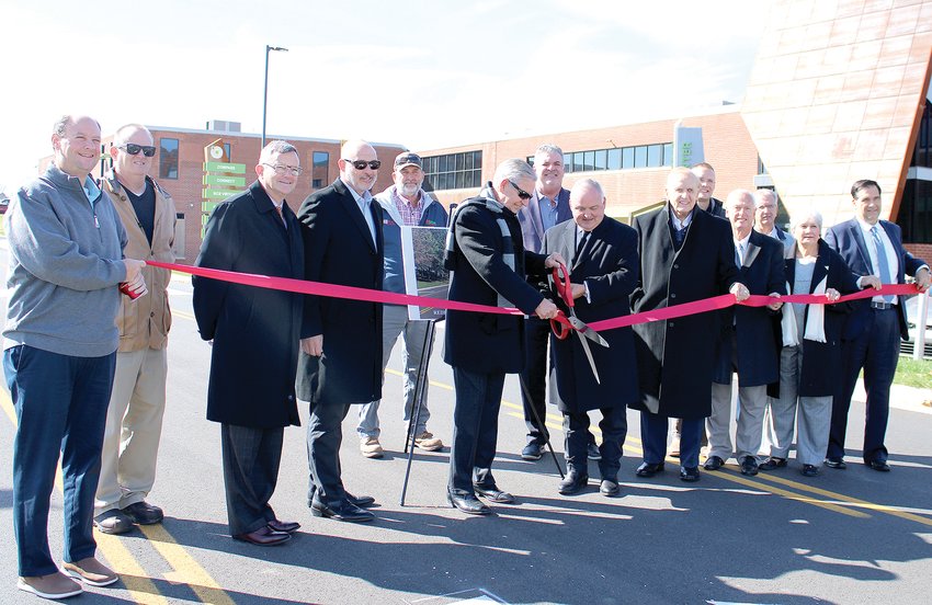 CITY OFFICIALS gather for a ribbon-cutting ceremony marking the completion of improvements to Parker Street near the PIE Innovation Center. In this photo, Cleveland Mayor Kevin Brooks, right, assists as Cleveland Councilman David May, left, cuts the ribbon.