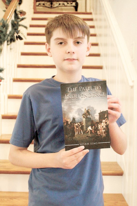 NOAH SIMS, 13, holds a hardback copy of his debut book, &quot;The Path To Independence.&quot;
