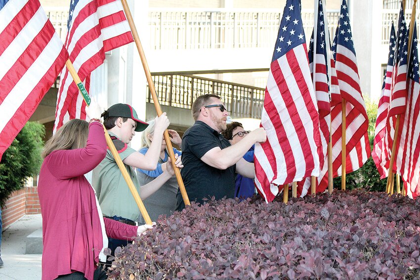 LEIGH ANN BOYD, DAR Ocoee Chapter regent, left; and Brian Heusterberg, Veteran's Services Office director, right, plant flags.