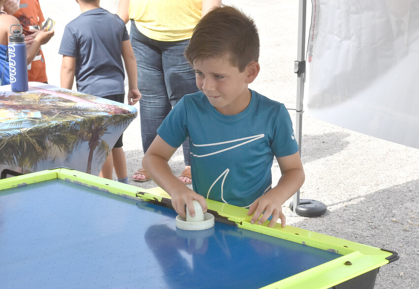 Truman Tomme of Aledo tries his skill at an air hockey table at the Grand Adventure booth.