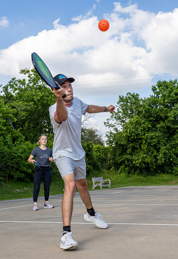 Zac Hess makes a play for the ball during a local pickleball match at the Aledo United Methodist Church while his wife and doubles partner, Hailey Hess, looks on.