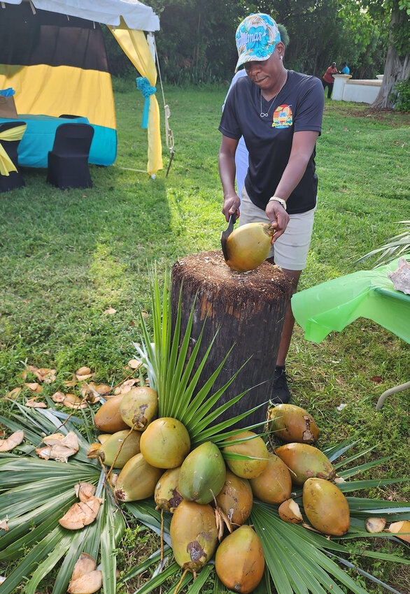 A lady chops up a fresh coconut in preparation to make Gully Washes, the unofficial drink of The Bahamas.