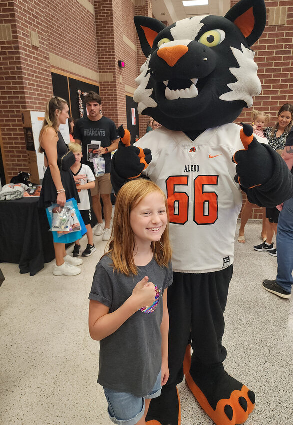McCall Elementary third-grader Chloe Headley visits with the Aledo Bearcats mascot.