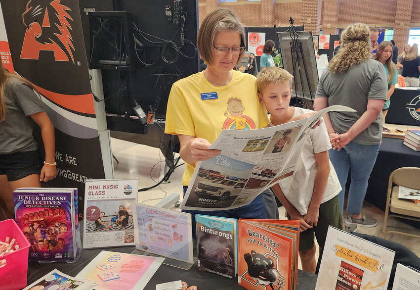 Tracy Lambert-Jack and Wyatt Jack read a copy of The Community News at the East Parker County Library booth.