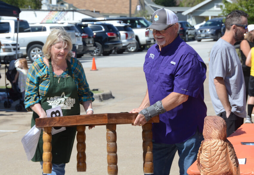 Steve and Sally Bond carry a custom coffee table which was donated to the live auction.