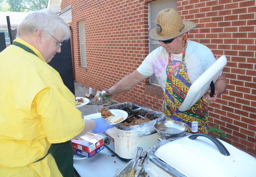 Craig Rogers and “Fireman Steve” Green, a former fire chief of Station 37 in Annetta, serve hamburgers and pulled pork sandwiches.