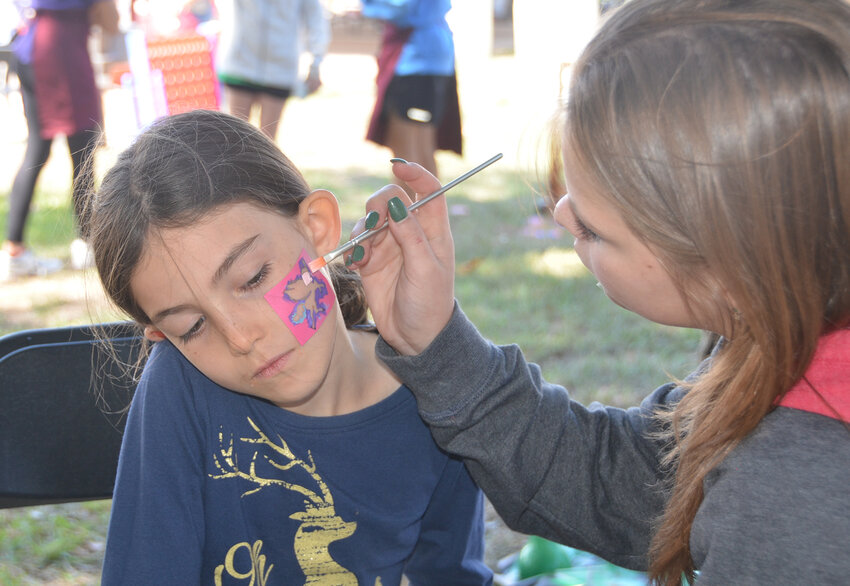 Vandagriff Elementary School student Ellie Kerr receives face art from volunteer Madie Madewell.
