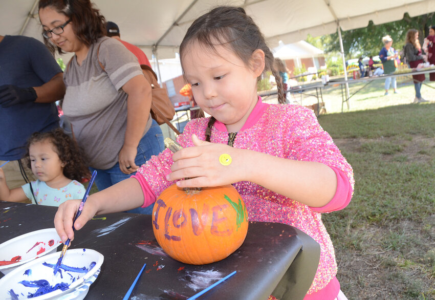 Walsh Elementary School student Alexandra Iandoli paints a heart on the back of her “I Love You” pumpkin.