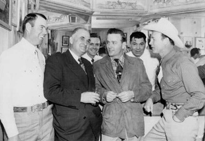 Bob Rothel, O.C. Whitaker, Unknown, Jimmy Wakely, Jack Dempsey, and Roy Rogers are shown in front of the bar..