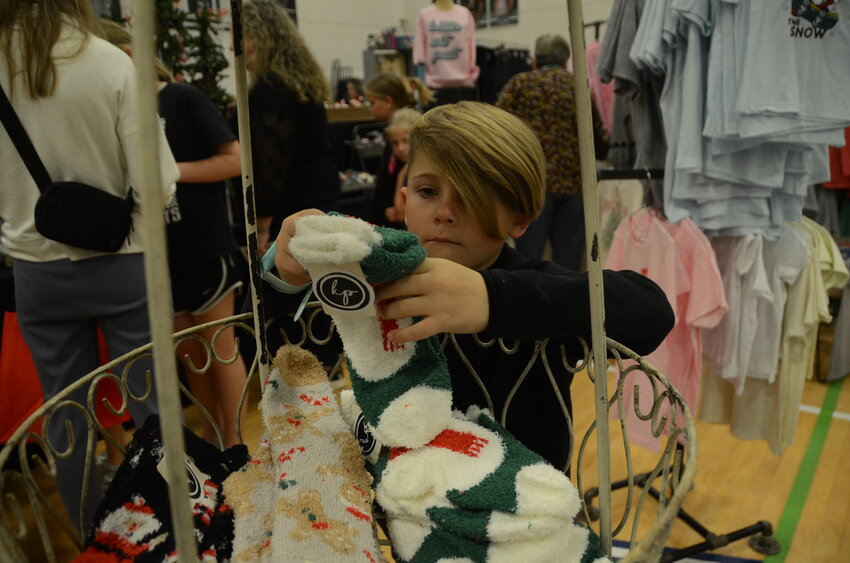 Grey Quinlan sizes up fuzzy holiday socks on display. Quinlan is a first-grader at Stuard Elementary.