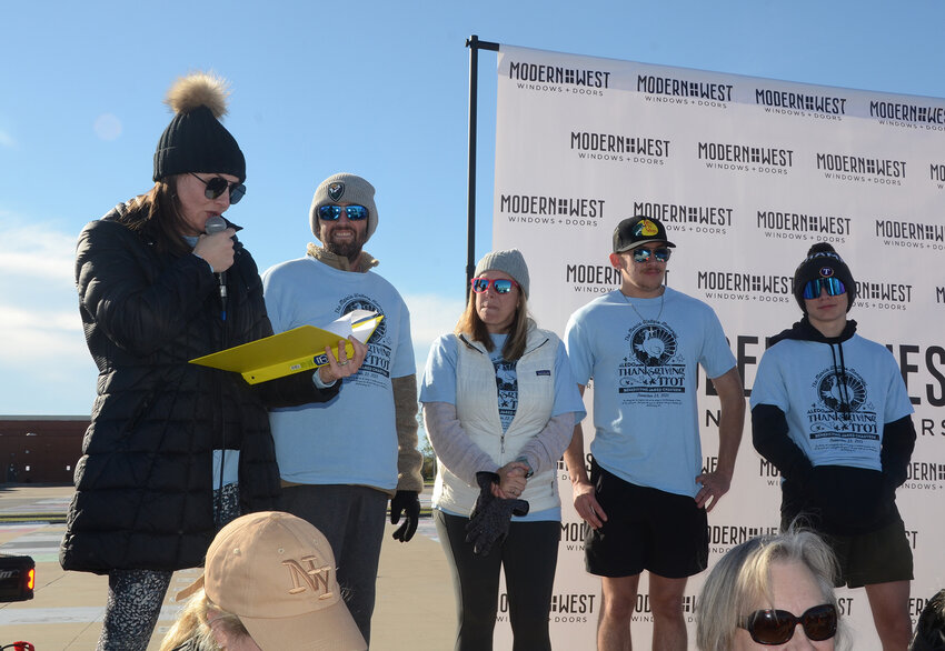Thanksgiving Trot co-chair Niki Thompson announces the big moment to recipient Jared CHasteen, wife Adeana, and sons Andrew and Noah.