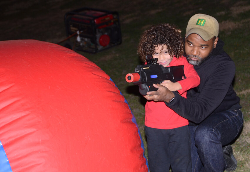 Kahlil Bowen takes cover with his son, Nolal, in a fast-moving laser tag game.