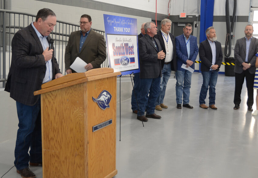 WISD Superintendent Beau Rees and Weatherford School Board President Mike Guest gather at the podium with school board members, Grizzard family members, and representatives of Southwest Ford, which donated six auto lifts for the new facility.