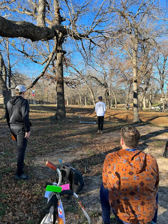 Golfers hike through some trees while playing on the Weatherford Disc Golf Course.